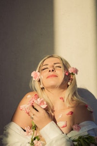a woman wearing a white shirt with flowers in her hair